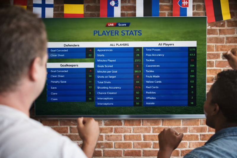 Two Football Fans Watching TV With Stats on the Screen